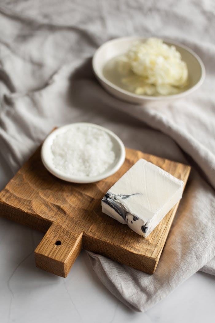 Elegant marble soap on textured wooden board with bath salts.